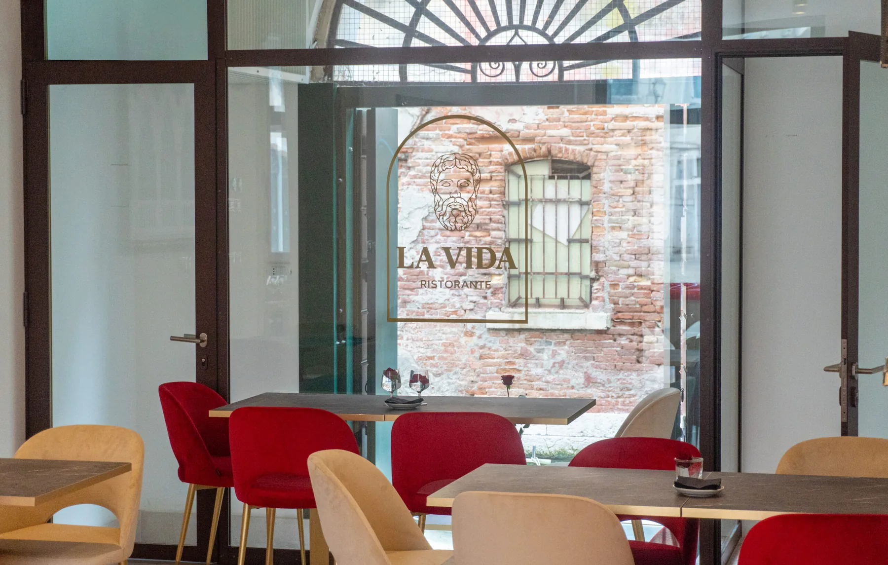 La sala di La Vida con la grande vetrata sul canale e il logo con l'arco di pietra.