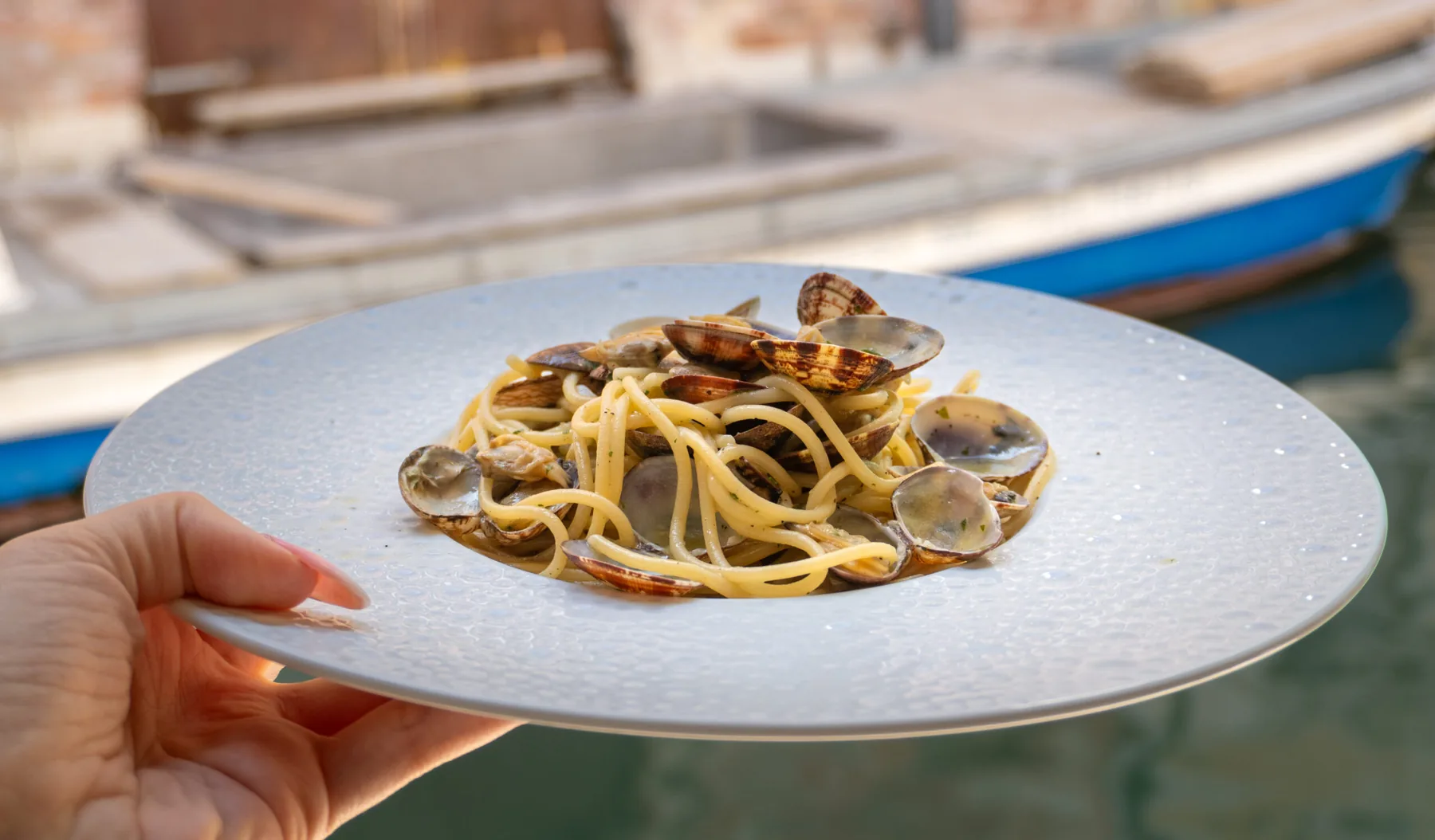 Piatto di spaghetti alle vongole con il canale sullo sfondo.